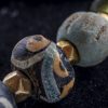 vaghi di scavo in vetro avvolto variamente decorato. Vago centrale in faience color turchese. Distanziatori in oro